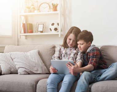 Kız ve erkek kardeş evde dijital tablet üzerinde oynama
