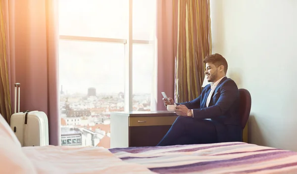 Empresário sorrindo usando telefone no quarto de hotel — Fotografia de Stock