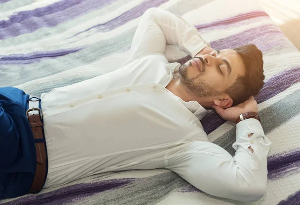 Hombre de negocios guapo acostado en la cama en la habitación del hotel —  Fotos de Stock