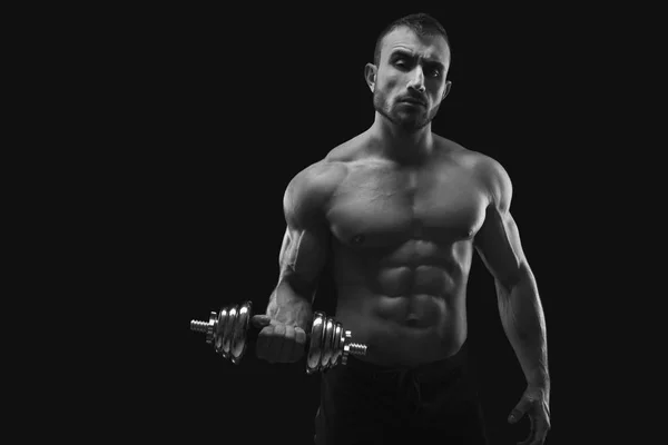 Сильный мужчина с гантелями показывает мускулистое тело — стоковое фото
