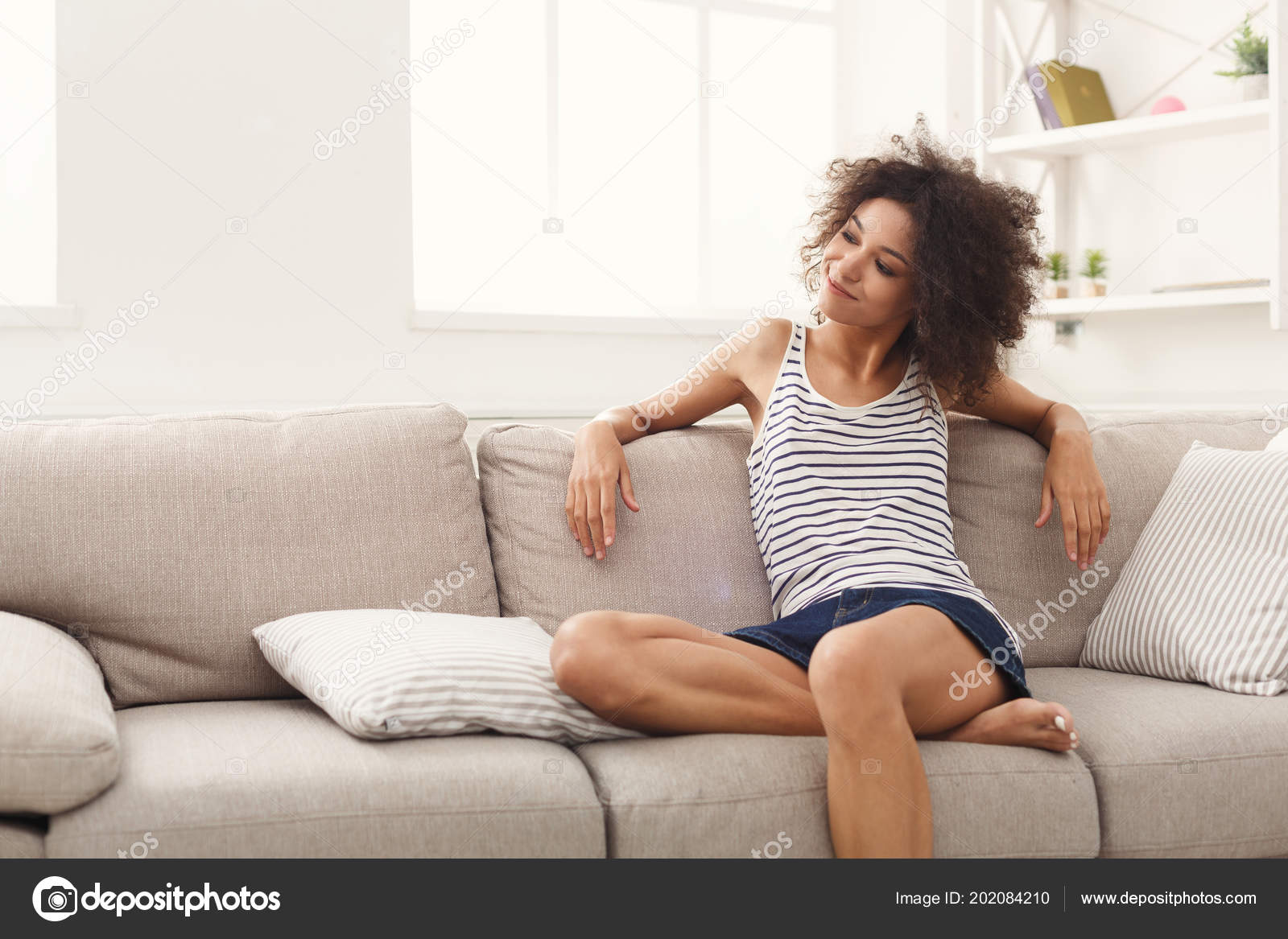Young happy woman on couch Stock Photo by ©Milkos 202084210