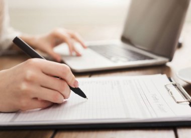 Kadın Yardımcısı rapor üstünde laptop kontrol