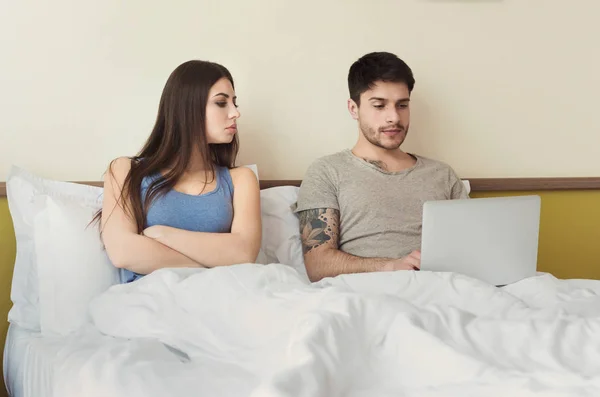 Ревнивая жена смотрит на ноутбук, пока муж печатает — стоковое фото