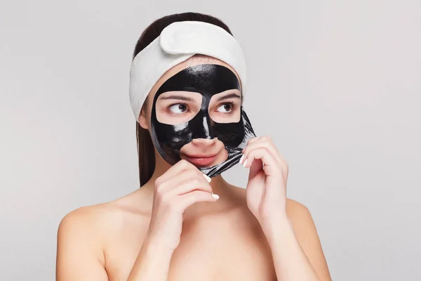 Giovane ragazza con maschera purificante viso nero — Foto Stock