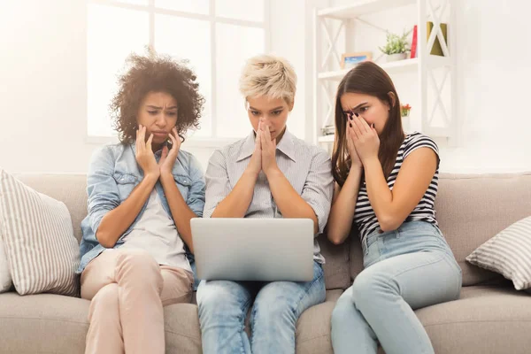 Three sad women using laptop at home