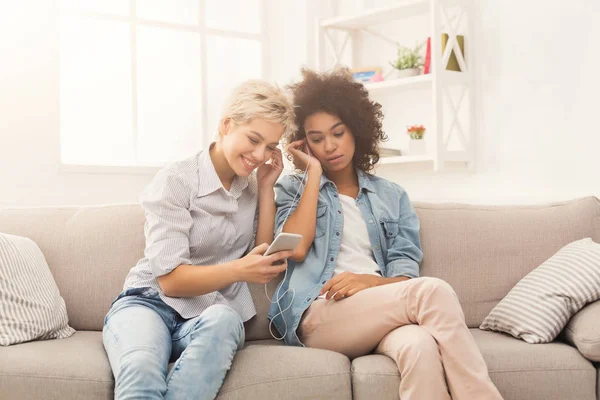 Dos mujeres escuchando música y compartiendo auriculares — Foto de Stock