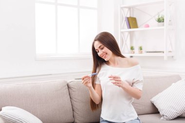 Hamilelik testi koltukta oturan ile gülümseyen genç kadın