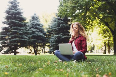 Bir dizüstü bilgisayar açık havada kullanan güzel genç kadın