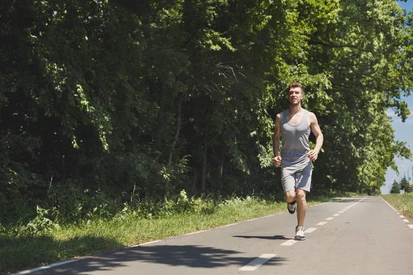 Junger Mann joggt auf Laufband im Park — Stockfoto