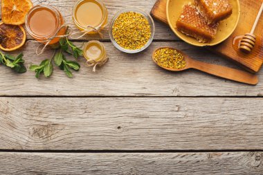 Rustik ahşap üzerine bal ürün yelpazesine sahip. Üstten Görünüm tam Cam Kavanoz, peteğin, polen kase, fındık, zencefil, nane ve kuru portakal. Tatlı arka plan, duvar kağıdı. Doğal Tıp kavramı, kopya alanı