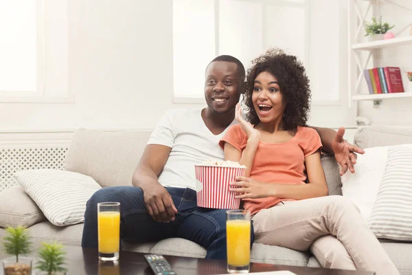 Happy african-american couple watching TV at home — Stock Photo, Image
