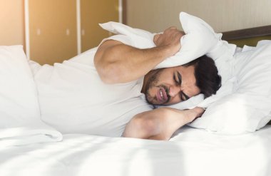 Genç adam kapsayan kulakları ile yastık uyumaya çalışıyor