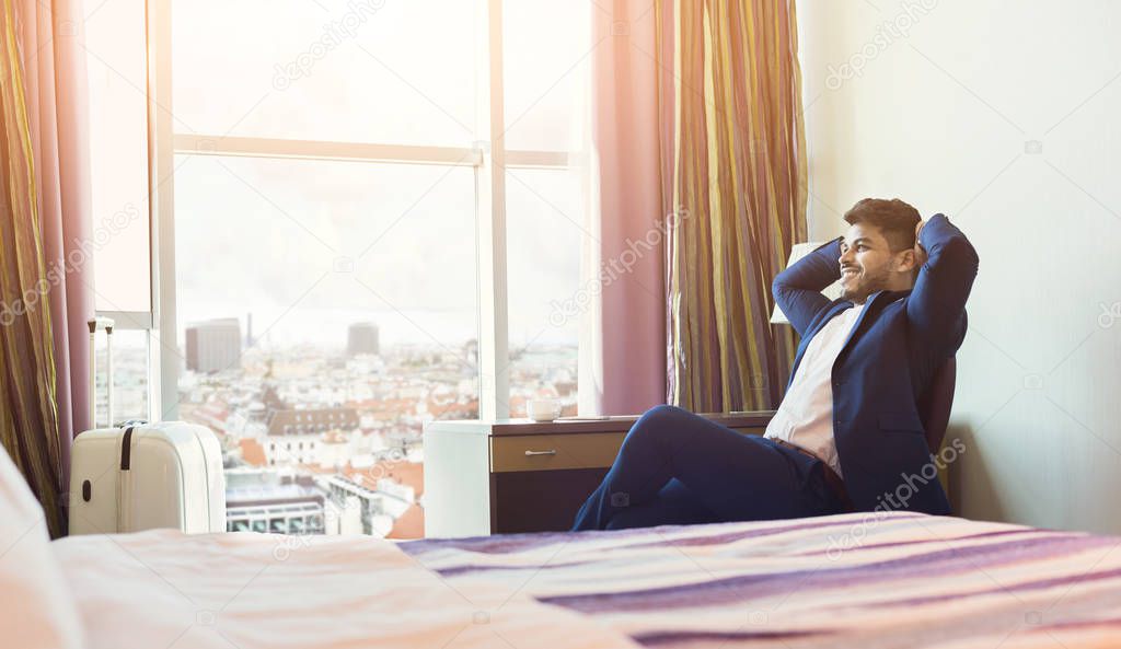 Young businessman with luggage in hotel room