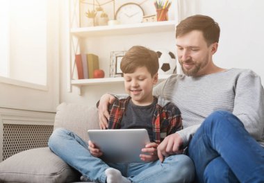 Baba ve oğul kullanarak evde kanepede birlikte tablet