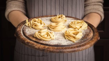 Kadın şef fettuccine yuva ile ahşap tepsi tutarak