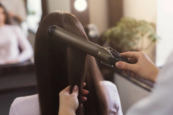 Kapper met behulp van krultang op de salon van de schoonheid — Stockfoto