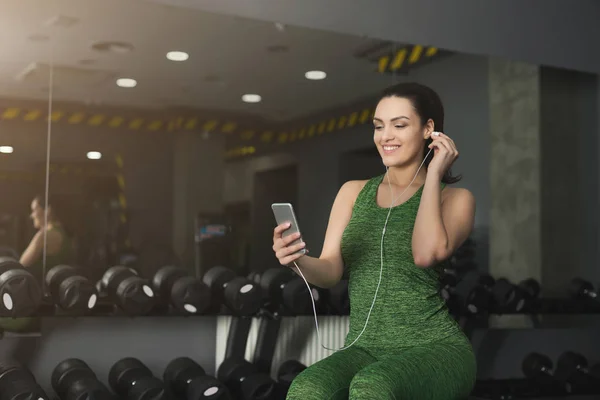 Chica de fitness en los auriculares elegir la música en el teléfono — Foto de Stock