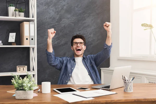 Молодой счастливый бизнесмен в офисе с компьютером — стоковое фото