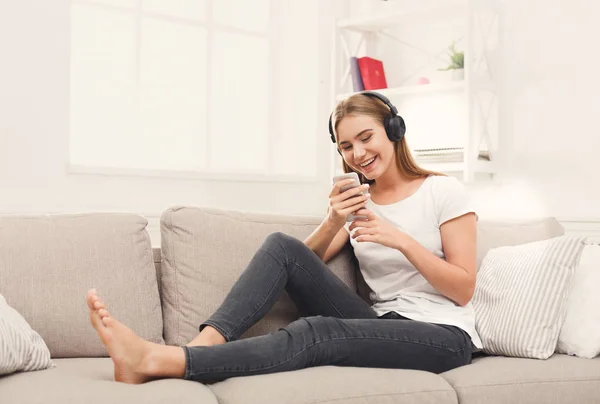Mujer joven feliz en auriculares en sofá beige — Foto de Stock