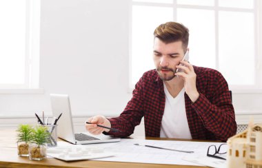 Konsantre genç mimar olan mobil telefon konuşma