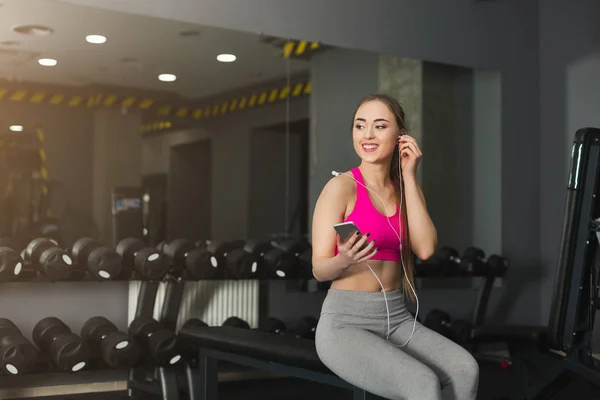 Chica de fitness en los auriculares elegir la música en el teléfono — Foto de Stock