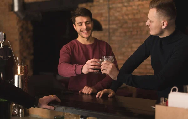 Två lyckliga unga män prata och dricka öl på bar — Stockfoto