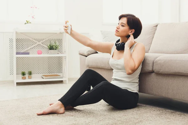 Jeune femme avec casque faisant selfie à la maison — Photo