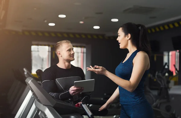 Entrenador de fitness ayuda a la mujer en el entrenador elíptico — Foto de Stock