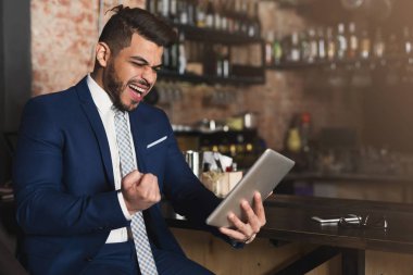 Euphoric businessman winning and watching at tablet clipart