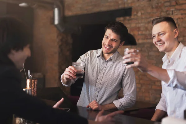 Веселые друзья в баре общаются с барменом — стоковое фото