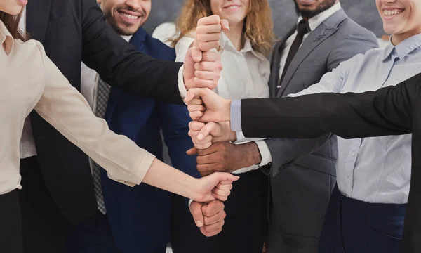 Positive business people putting fists on top of each other — Stock Photo, Image