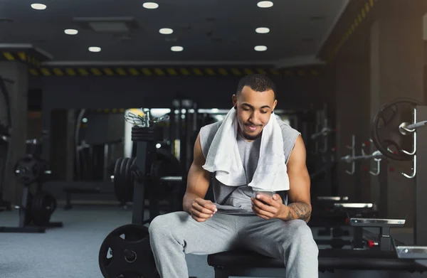 Svart bodybuilder använder mobiltelefon på gym — Stockfoto