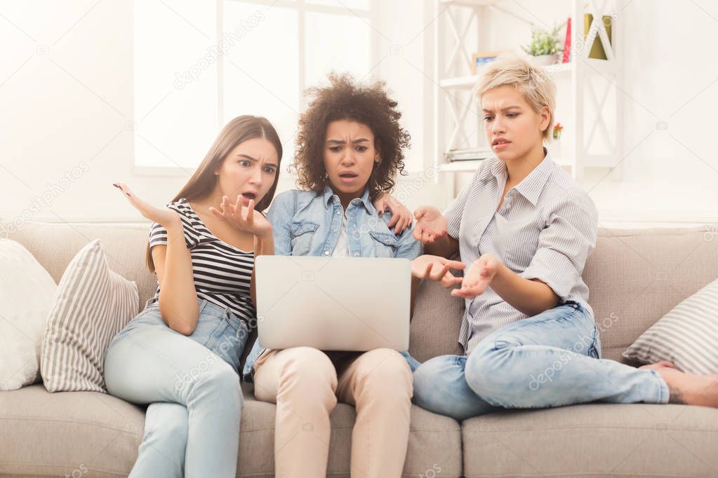 Three beautiful shocked women using laptop at home