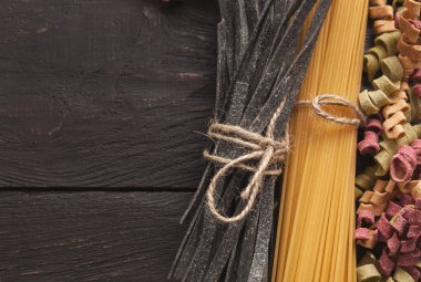 Renkli İtalyan makarna ve pişirme malzemelerin üzerine ahşap masa