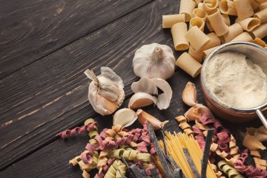 Renkli İtalyan makarna ve pişirme malzemelerin üzerine ahşap masa