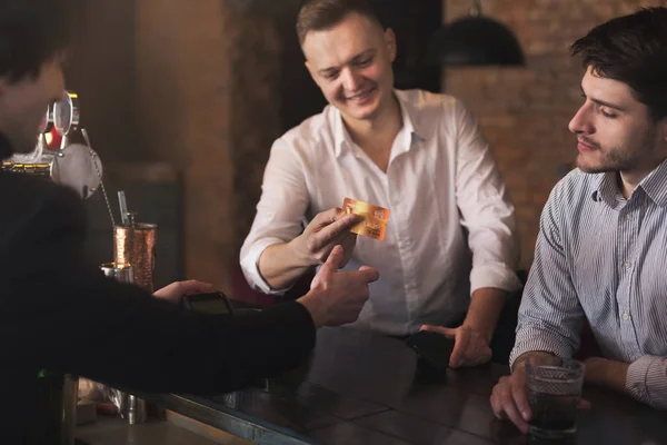 Hombre dando tarjeta de crédito al camarero en el pub — Foto de Stock