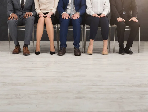 Personas sentadas con las manos en las rodillas en fila — Foto de Stock