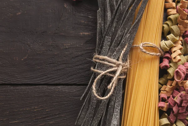 Renkli İtalyan makarna ve pişirme malzemelerin üzerine ahşap masa