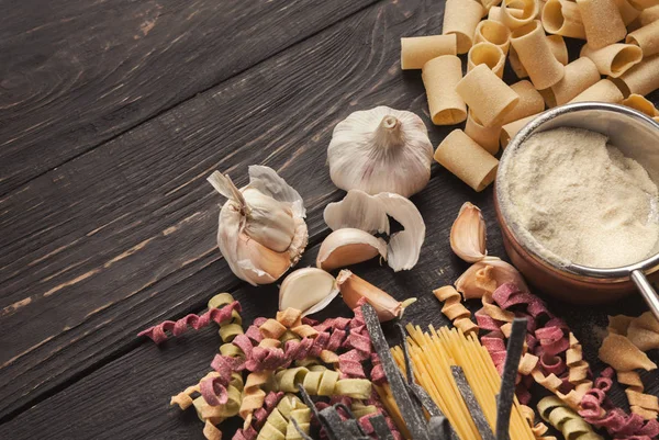 Renkli İtalyan makarna ve pişirme malzemelerin üzerine ahşap masa