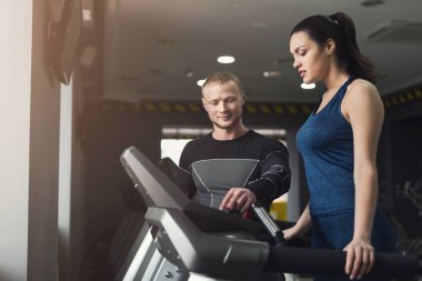 Spor hocası eliptik eğitmen kadına yardımcı olur.