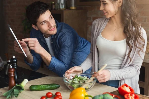 Beautiful young couple reading recipe on tablet — Stock Photo, Image
