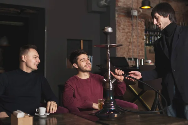 Two young men ordering hookah in cafe