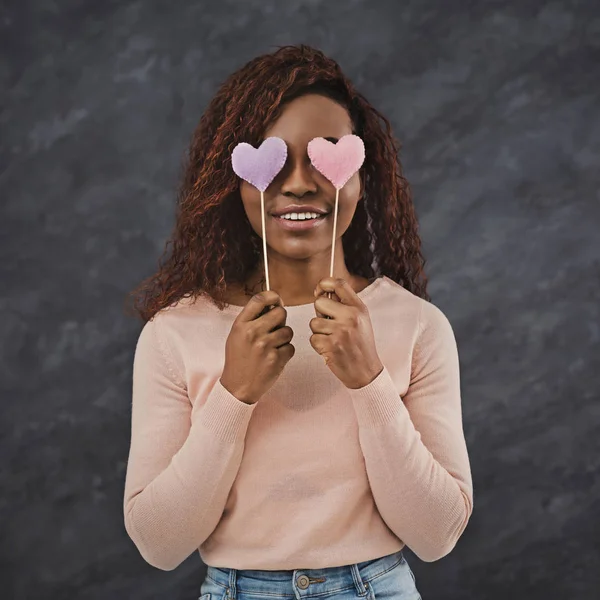 Chica africana alegre cubriendo los ojos con corazones de San Valentín — Foto de Stock