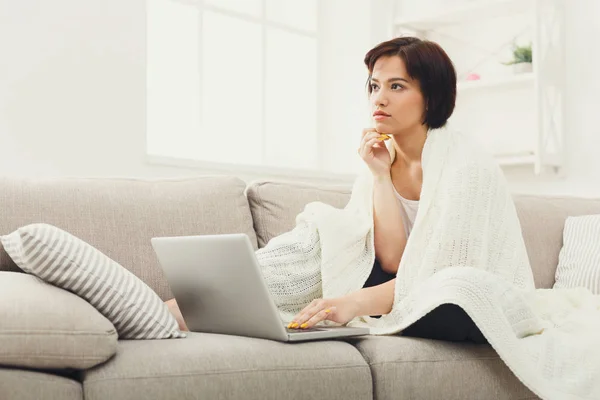 Girl in a blanket working with a laptop