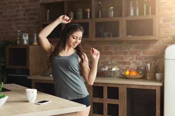 Щаслива молода жінка слухає музику на кухні — стокове фото