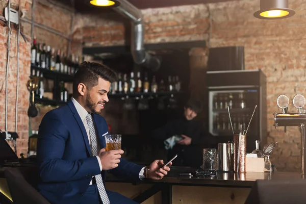 Jonge man achter de toog zit en het gebruik van smartphone — Stockfoto