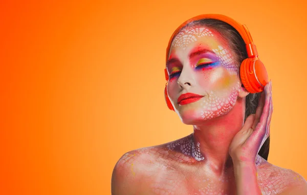 Mujer hermosa brillante en auriculares naranjas — Foto de Stock