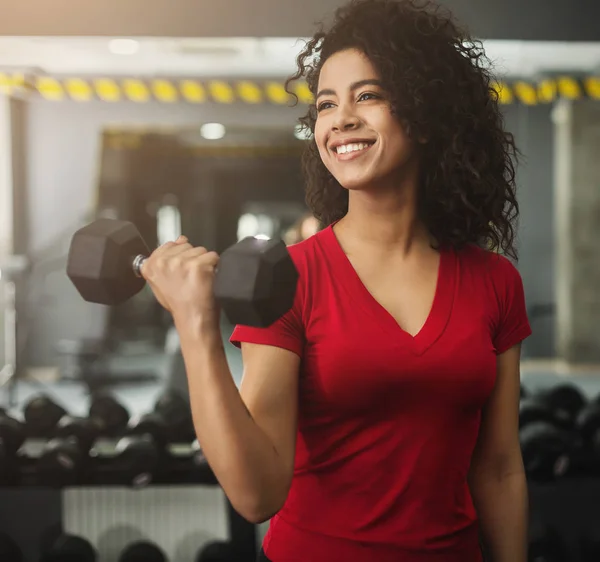 Mulher feliz fazendo exercícios com halteres no ginásio — Fotografia de Stock