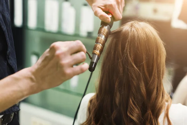 Peluquero hacer hermosos rizos con rizador en el pelo del cliente —  Fotos de Stock