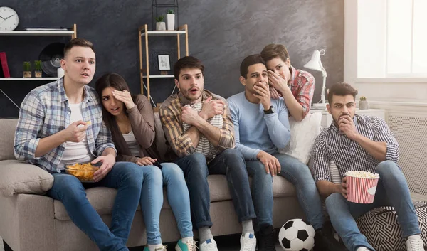 Schockierte multiethnische Freunde, die zu Hause Film schauen — Stockfoto